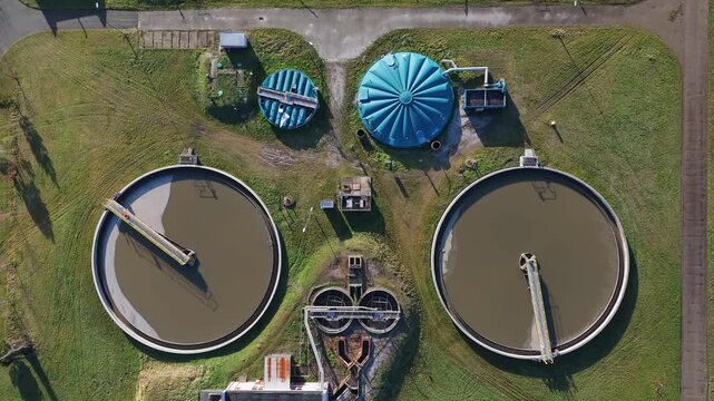 A drone flight over a wastewater treatment plant reveals circular clarifiers, technical infrastructure, green areas and mechanical biological sewage treatment processes