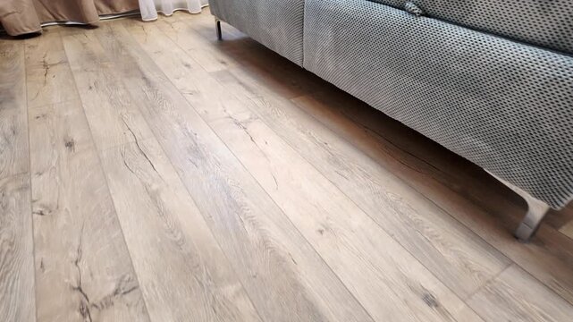 Natural wood laminate parquet floor. Room with floating laminate in new apartmen. Cozy home interior, modern design