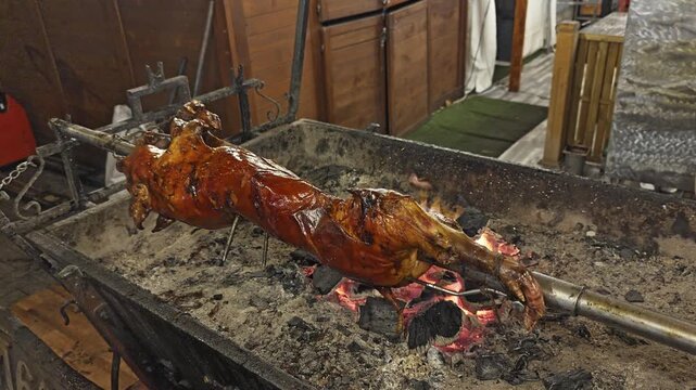 Whole Roasted Suckling Pig on Spit Over Charcoal Fire, Traditional Barbecue Cooking with Crispy Golden Skin, Authentic Street Food and Festive Culinary Celebration