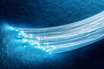 Bundle of optical fibers with lights in the ends. Blue background.