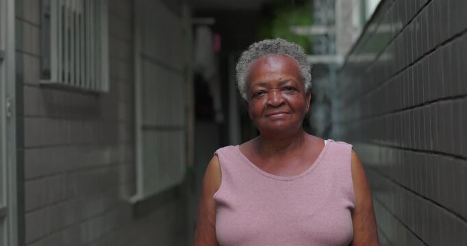 Elderly African American woman standing in corridor with soft smile, quiet grace, strength, warmth, and everyday dignity shaped by life experience