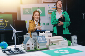 
 Two business people team planning and discussing of sustainable and renewable clean energy product with solar cell and wind turbine generator, CO2 emissions climate change global warming project