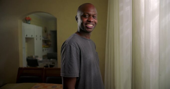 African American man standing by window at home smiling calmly, relaxed mood, everyday domestic moment, quiet confidence, natural human presence