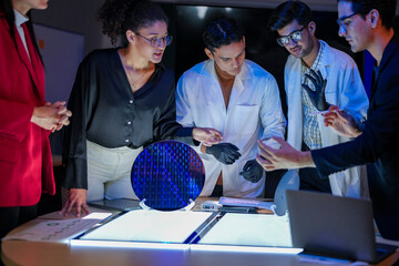 engineering research group analyzing a silicon wafer prototype. Professors and students collaborating on a microchip physics experiment in laboratory to develop future electronic technology.