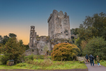 The exterior of Blarney Castle, a medieval stronghold in Cork, Ireland, captured in autumn under a moody sunset sky