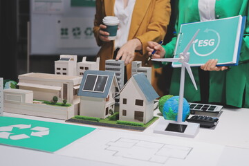 
 Two business people team planning and discussing of sustainable and renewable clean energy product with solar cell and wind turbine generator, CO2 emissions climate change global warming project