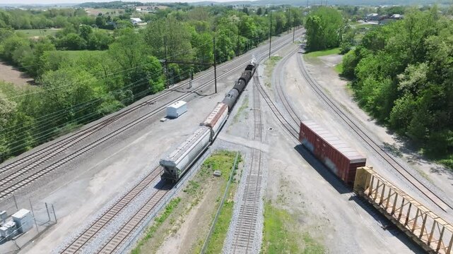 A vintage steam freight train makes its way backing up in yard performing switching operations moving steadily along the railway tracks in a peaceful countryside setting.