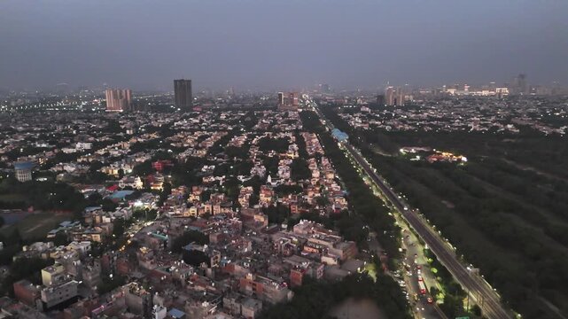 Aerial night view of Noida&rsquo;s urban core, where elevated roads and metro corridors weave through dense neighborhoods and rising skyscrapers, highlighting connectivity and modern city life.