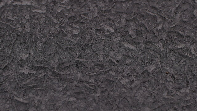 Winter natural pattern of frozen snowflakes on the hood of a car close-up