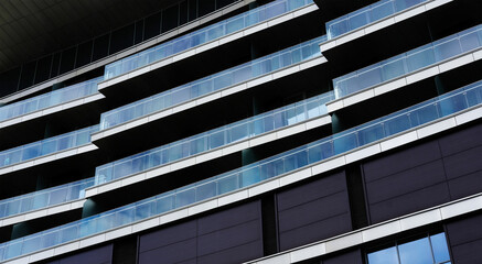 Modern architectural building with sleek glass balconies and dark panels, showcasing contemporary design elements and urban living aesthetics in a vibrant city environment