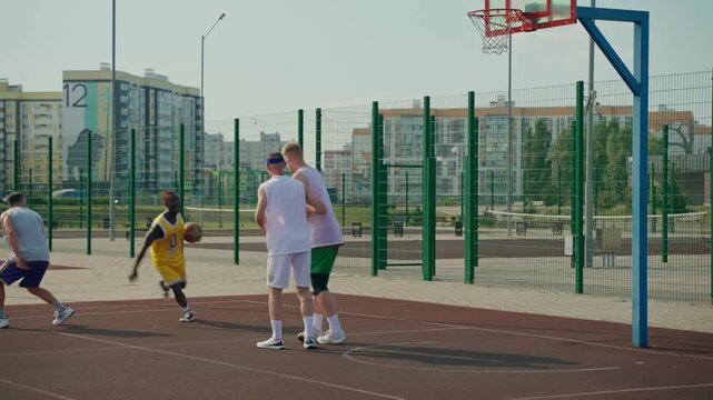 A player deftly bypasses the defense and throws the ball into the basket. A teammate intercepts the ball and scores a point.