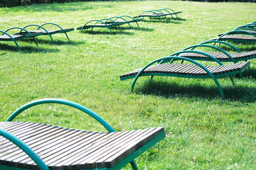 Lounge chairs arranged on a lush green lawn under bright sunlight, creating a serene outdoor...