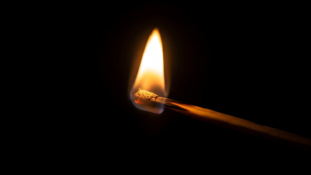 Close-up of a burning matchstick igniting in the dark, with a bright flame and glowing ember, symbolizing fire and ignition