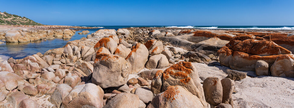 Panorama veiw of coastal granite boulders covered in lichen around a narrow inlet