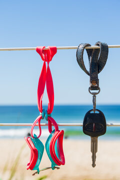 Close up of a car key and swimming goggles hanging on a fence at the beach