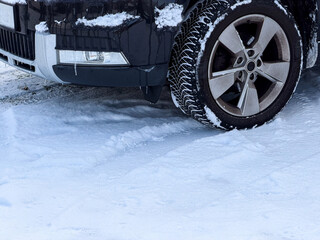 Close u of front car wheel standing on snow covered road 