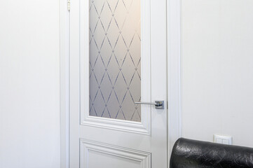 White interior door with frosted glass panel featuring a diamond pattern, sleek metallic handle,...