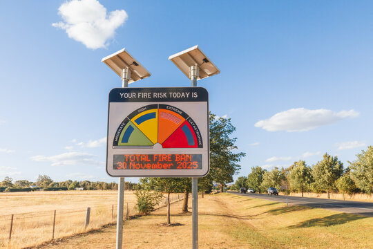 Extreme fire danger risk warning sign advising total fire ban in summer with traffic passing by