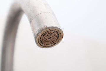 Macro of a kitchen faucet aerator clogged with limescale and mineral deposits.