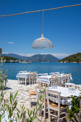 Served tables in a Greek tavern in Vathy Harbor, Meganisi island, Ionian Sea, Greece during the summer tourist season. 