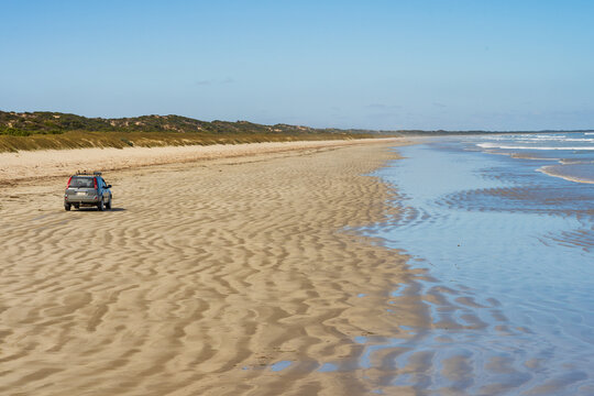 4WD on a beach with rippled sand and receeding waves