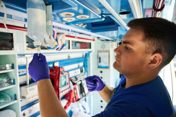 Male medic preparing iv drip in ambulance