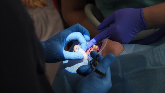 Dental surgery with surgeon at work. dentist makes anesthesia injection to patient with absent front teeth before treatment. Dentist injects local anesthetic into gums. No pain concept. Medicine and