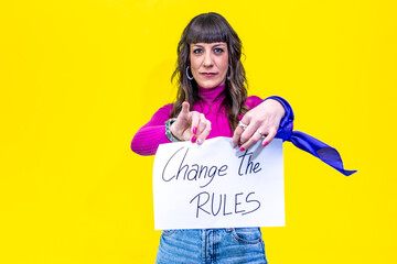 Woman pointing at you while holding sign with change the rules written on it