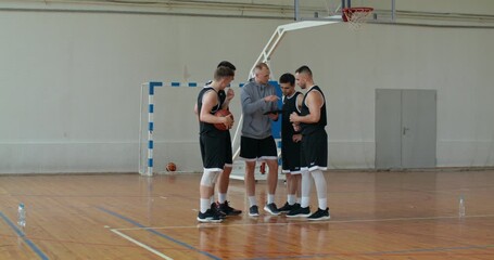 the coach is explaining the tactics of the game to the team. a coach and the team look at a tablet and discuss tactics for the upcoming game.