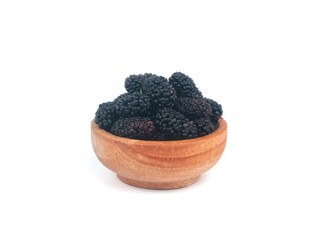 Fresh ripe black mulberries in a wooden bowl isolated on white background. Perfect for healthy eating, organic food, and harvest themes