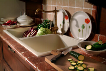 Close up of a kitchen sink, with various vegetables being prepared