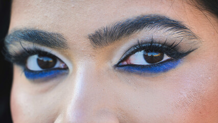 Fototapeta premium Bangladeshi girl wearing bold blue eye makeup looking at camera in Moscow