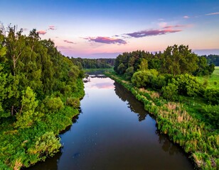 Fototapeta premium Serene aerial view of a river meandering through lush, green forest at dusk