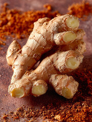 Close-up of fresh ginger root with ground ginger spice scattered around it