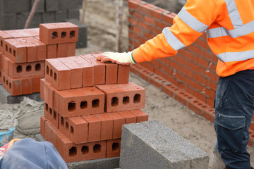 Bricklayer laying red bricks on building site