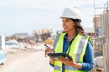 Young woman builder construction manager uses rugged tablet to record data on construction site © Iryna