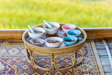 Traditional Thai Khantoke breakfast set on a rattan tray at a mountain homestay. Authentic local meal with rice porridge overlooking a scenic rural landscape.