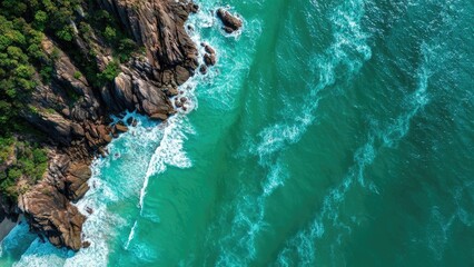 Aerial view of a rocky cliff coastline with dense green forest on the left and turquoise waves crashing along the rocks. Concept Aerial coastal landscape, Rocky cliff coastline