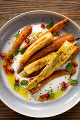 Roasted carrots and parsnips with greek yogurt on plate top view
