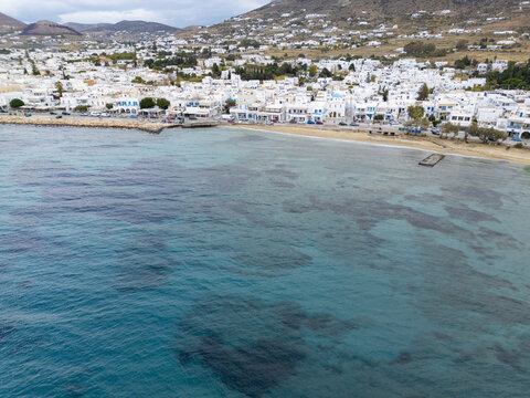 Aerial view of white buildings meet the turquoise sea, creating a serene coastal tableau, Paros, Paros, Greece.