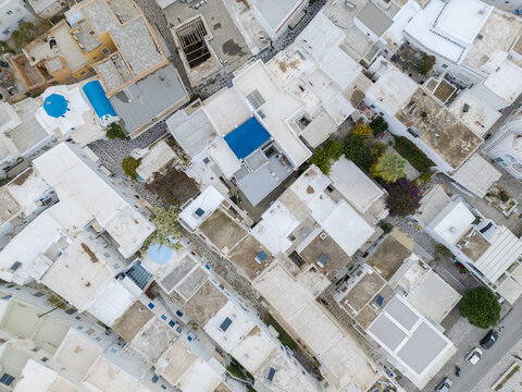 Aerial view of whitewashed buildings interspersed with vibrant blue rooftops and small gardens creating a captivating mosaic from above, Paros, Paros, Greece.