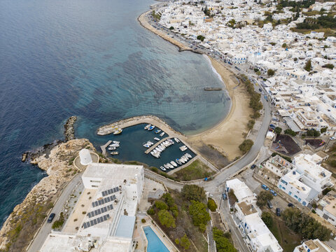 Aerial view of the curved bay embracing the sandy beach, with white buildings nestled against the azure sea, Paros, Paros, Greece.