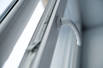 Low angle view of a window grip on a double glazed profile. Concept of hardware repair, room ventilation, and home renovation with blurred background. Photo
