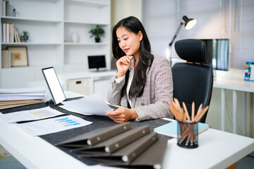 Successful and joyful woman at workplace checking financial reports and contracts. Businesswoman doing paperwork inside office, using tablet. Financier preparing and filling out tax forms