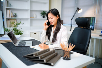 Young asian businesswoman beautiful charming smiling and talking on the mobile phone in the office.