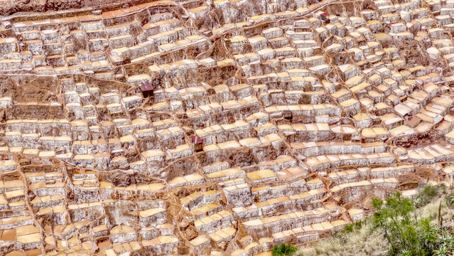 Aerial view of the patchwork quilt of terraced salt evaporation ponds glitters under the sun, a testament to ancient ingenuity, Maras, Peru.