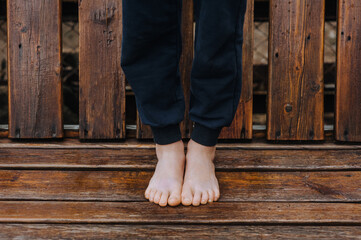 A little girl, a child stands barefoot on a wooden bench, doing yoga exercises. Photography, sports, health.