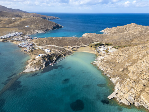 Aerial view of the turquoise waters embracing rocky shores and sandy beaches, a quaint village nestled between the bays, Paros, Paros, Greece.