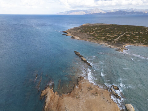 Aerial view of turquoise waters meet rugged, rocky shores, a dance of nature's artistry under the vast sky, Paros, Paros, Greece.