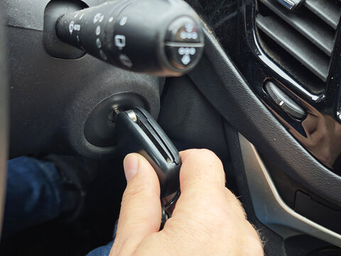 Hand turning car key in ignition switch inside vehicle interior, close-up automotive detail, engine start, transportation and driving routine